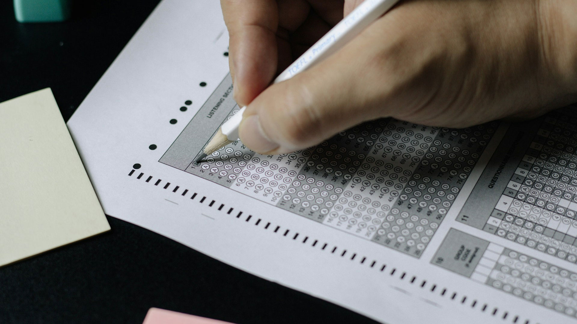 hand and pencil filling in test bubbles