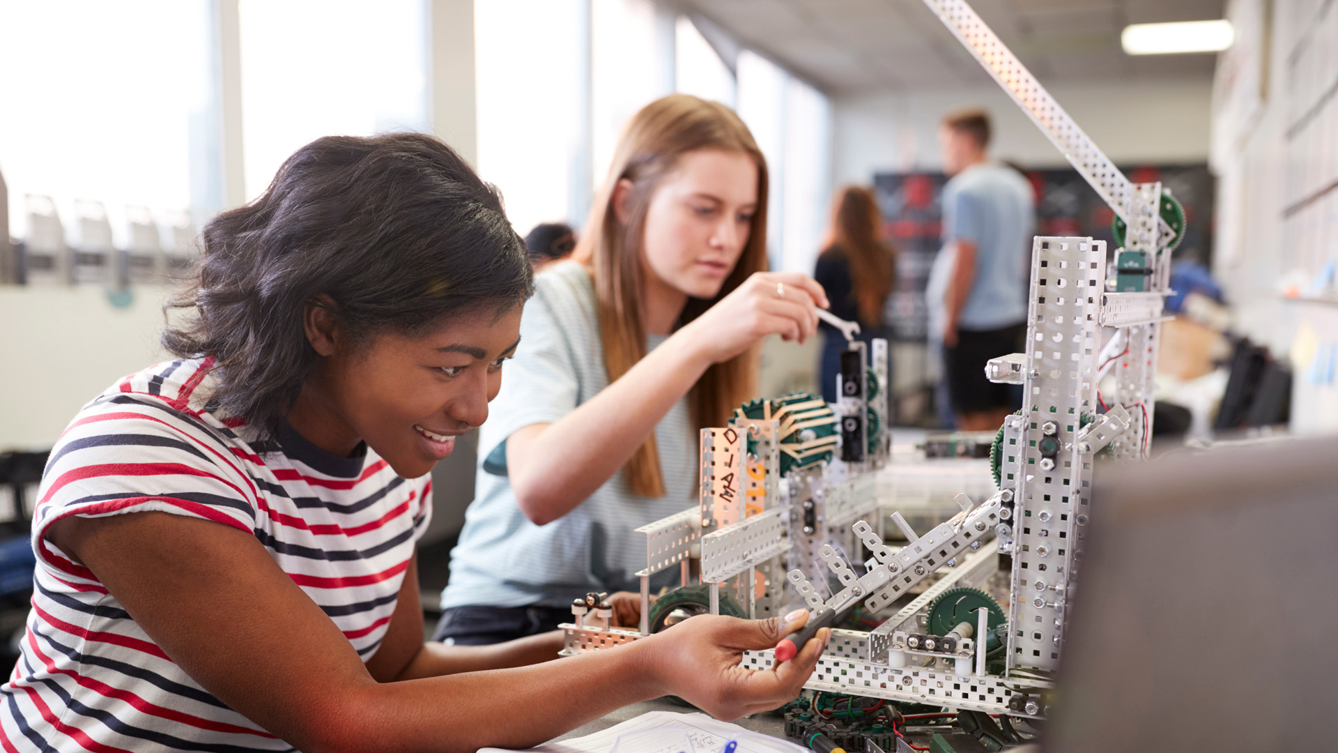 Two Female College Students Building Machine In Science Robotics Or Engineering Class