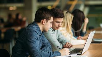 students sitting at table with laptop